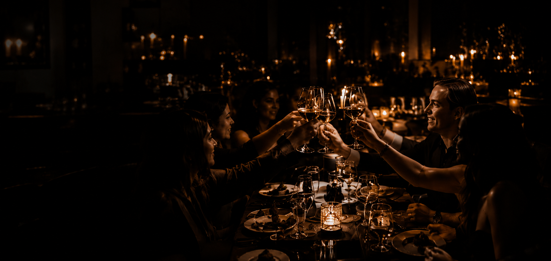 Gäster skålar med vin vid en stämningsfull middag i levande ljus